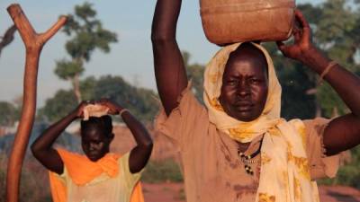 Mujeres cargando tinajas con agua en Sudan del Sur.