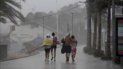 Un grupo de personas camina por una calle en el puerto mexicano de Acapulco donde se registran fuertes lluvias generadas por la tormenta tropical 'Marie' que se desplaza paralela a la costa occidental de México y que afecta a cinco estados del país. EFE/Archivo