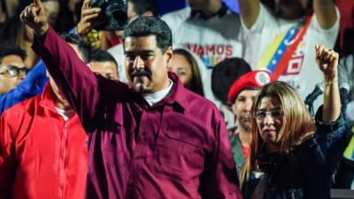 Venezuelan President Nicolas Maduro (L) gestures accompanied by his wife and first lady Cilia Flores after the National Electoral Council (CNE) announced the results of the voting on election day in Venezuela, on May 20, 2018.President Nicolas Maduro was declared winner of Venezuela's election Sunday in a poll rejected as invalid by his rivals, who called for fresh elections to be held later this year. With more than 90 percent of the votes counted, Maduro had 67.7 percent of the vote, with his main rival Henri Falcon taking 21.2 percent, the National Election Council chief Tibisay Lucena announced. / AFP PHOTO / Juan BARRETO