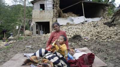 Varias personas permanecen junto a sus hogares destruídos tras el seísmo que azotó el país el pasado sábado en la aldea de Kumalpur, a las afueras de Katmandú, Nepal. EFE