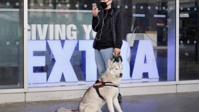 Un hombre se protege con una mascarilla mientras pasea en el centro de Londres con su perro. Foto: AFP/Referencia