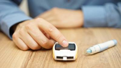 man testing glucose level with a digital glucometer, diabetes treatment