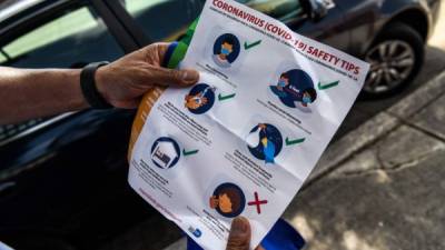 A member of the Miami-Dade County 'surge teams' holds a pamphlet as he distributes bags with masks, sanitizers, and gloves to educate people on how to stay safe from COVID-19, in a neighbourhood of Miami, Florida on April 30, 2020. - House to house, a group of Florida's workers hand out masks and sanitizers in Miami, trying to convince neighbors to use them in an ant effort to combat the surge in coronavirus cases. (Photo by CHANDAN KHANNA / AFP)