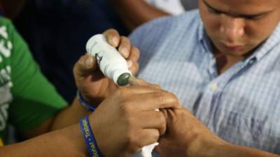 Un hondureño es manchado de tinta en su dedo después de votar en las primarias.