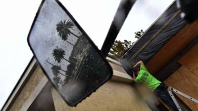 Un residente de Atlantic Beach, Florida, en la ruta del huracán Matthew protege un negocio con cpn tablas de plywood. Foto: AFP