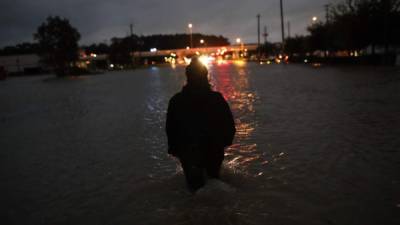 Una residente de Houston camina a través de las aguas mientras evacua su hogar después de una inundación severa después del huracán Harvey. AFP