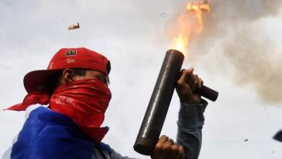 An anti-government demonstrator fires a homemade mortar in Managua, Nicaragua on June 17, 2018, demanding justice for the death of six members of a single family who died when their house was burnt at dawn on Saturday after a group of men armed wearing hoods threw a Molotov cocktail. / AFP PHOTO / MARVIN RECINOS