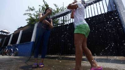 Dos sampedranas se las arreglan para refrescarse. Foto: Wendell Escoto