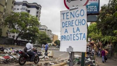 Transeúntes caminan junto a una barricada hecha con basura y escombros, en las calles del sector El Cafetal, en Caracas (Venezuela). EFE