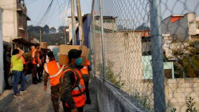 Soldados del Ejercito de Guatemala y policías reparten cajas con comida básica en el asentamiento Santa Rosita, este lunes, en Ciudad de Guatemala (Guatemala). EFE/Esteban Biba