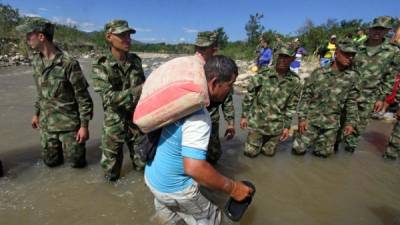Un colombiano es ayudado por soldados colombianos mientras cruza el río Táchira en dirección a Colombia tras ser expulsado por Venezuela.