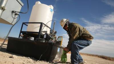 Un empleado de Stewarts Inc., una compañía de servicios petroleros en Texas, trabaja sobre un tambor de químicos en un sitio de perforación en el yacimiento de crudo.