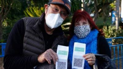 Una pareja israelí muestra su pase sanitario que les permite ingresar a establecimientos como restaurantes y gimnasios./AFP.