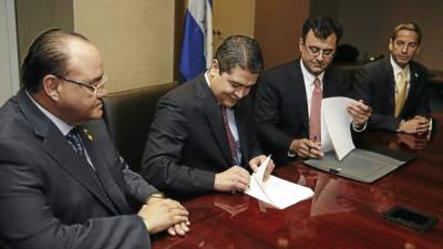 El ministro de Insep, Roberto Ordóñez, el presidente Juan Orlando Hernández y representante de General Electric en la firma del acuerdo.
