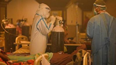 TOPSHOT - Health workers wearing personal protective equipment (PPE kit) attends to Covid-19 coronavirus positive patients inside a banquet hall temporarily converted into a covid care centre in New Delhi on April 28, 2021. (Photo by Prakash SINGH / AFP)