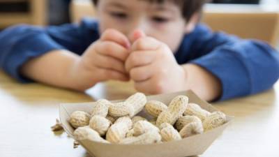 Little boy opening up peanuts to eat in a restaurant