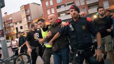 Un agente de la guardia civil española es escoltado por agentes de la policía catalana.