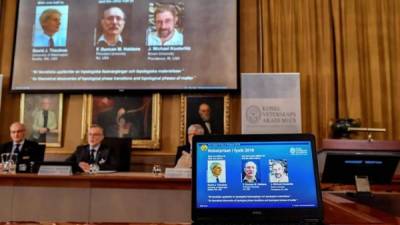 Imagen de una pantalla en la Academia de Ciencias de Estocolmo, Suecia, que muestra a los científicos británicos David Thouless, Duncan Haldane y Michael Kosterlitz. EFE.