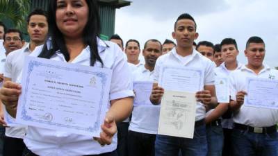 Estudiantes recién graduados muestran su título de técnicos en diferentes carreras.