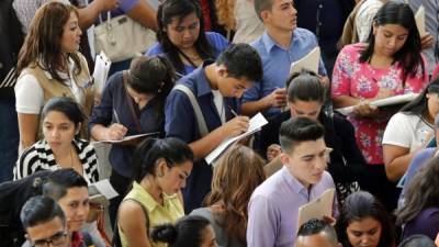 Muchos jóvenes capitalinos contestan formularios, mientras aguardan su turno para ser llamados en una feria de empleo.