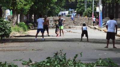 Children play baseball between barricades in Masaya, Nicaragua on June 20, 2018.Masaya, once a stronghold of Ortega's Sandinista revolution, has been a focal point of protests aimed at forcing him out of office. The city which has turned into a war zone with streets blocked by rubble and barricades, declared itself to be in rebellion against the government. / AFP PHOTO / MARVIN RECINOS