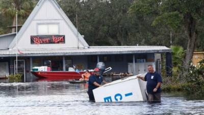 Dos hombres trasladan un congelador por una calle inundada del poblado de Arcadia (Florida).