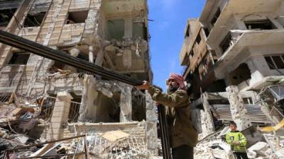 Un hombre sirio rescata elementos de los escombros en Douma en las afueras de Damasco. AFP