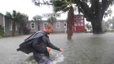 Un hombre camina por las calles inundadas.