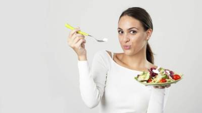 Woman eating salad isolated on white