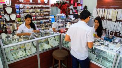 Dos empleadas de una tienda de bisutería ubicada en el barrio Guamilito atienden a un joven. Foto: Wendell Escoto