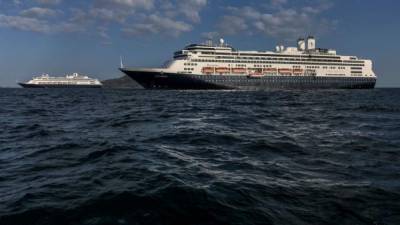 Holland America's cruise ship Zaandam (L) and the Rotterdam cruise ship are seen in Panama City bay on March 28,2020. - Earlier Saturday, Panama's maritime authority said healthy passengers were being evacuated from the Zaandam to another liner, the Rotterdam. The Zaandam cruise ship has been stranded at sea since March 14 after several South American ports refused to let it dock due to dozens of people aboard having shown flu-like symptoms. (Photo by Ivan PISARENKO / AFP)