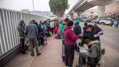 Un grupo de migrantes venezolanos, guatemaltecos, hondureños y mexicanos esperan para iniciar la solicitud de visa humanitaria afuera de la oficina fronteriza estadounidense de El Chaparral, en la frontera de la ciudad de Tijuana, en el estado de Baja California, con Estados Unidos. EFE/Alonso Rochin/Archivo