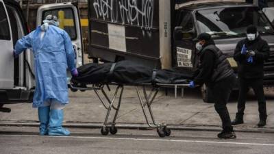 NEW YORK, NY - APRIL 27 : A funeral worker is assisted moving a deceased patient into a van at the Brooklyn Hospital Center on April 27, 2020 in the Brooklyn borough of New York City. The Brooklyn Hospital Center has been part of the pandemic's epicenter in New York City. Stephanie Keith/Getty Images/AFP== FOR NEWSPAPERS, INTERNET, TELCOS & TELEVISION USE ONLY ==