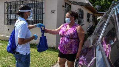 Personal sanitario reparte mascarillas casa por casa para intentar frenar la propagación del coronavirus./AFP.