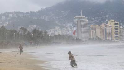 A resident rides his bike, past a fallen tree, after the passage of Hurricane Willa in Escuinapa, Sinaloa state, Mexico, on October 24, 2018. - Hurricane Willa crashed ashore in western Mexico Tuesday, lashing the Pacific coast with powerful winds and heavy rain before weakening to a tropical depression as it moved inland. (Photo by ALFREDO ESTRELLA / AFP)