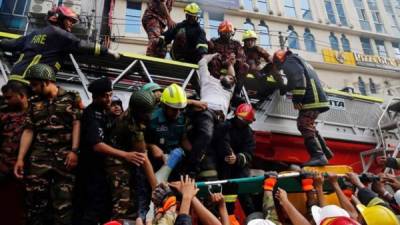 Miembros del cuerpo de bomberos de Bangladesh rescatan a varias personas que se hallaban en un edificio donde se ha producido un incendio en Dacca, Bangladesh. Aumentan a 25 los muertos en el incendio de un rascacielos ocurrido en Bangladesh. EFE