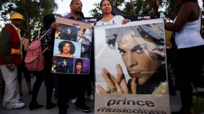 Fanáticos del fallecido músico estadounidense Prince sostienen carteles con su imagen el jueves 21 de abril de 2016, durante un encuentro de seguidores para celebrar su vida y obra.