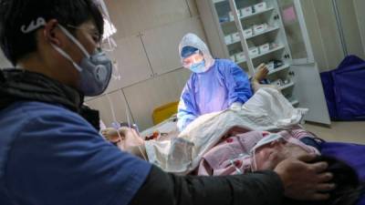 TOPSHOT - In this photograph taken on February 22, 2020 a pregnant woman wearing a protective facemask gives birth at a hospital in Wuhan in China's central Hubei province. - A group of volunteers in Wuhan works on helping pregnant women to go to hospitals in the quarantined city during the COVID-19 coronavirus outbreak. (Photo by STR / AFP) / China OUT