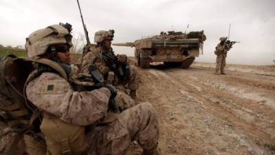 (FILES) In this file photo US marines with 1/3 marine Charlie Company patrol past a Danish army Leopard 2A5EK tank as they clear Improvised Explosive Device (IED)s from a main route in Trikh Nawar on the North Eastern outskirts of Marjah on February 21, 2010. - President Joe Biden will remove all US troops from Afghanistan before this year's 20th anniversary of the September 11 attacks, ending America's longest war around five months later than planned, a US official said.Biden has 'reached the conclusion that the United States will complete its drawdown -- will remove its forces from Afghanistan -- before September 11,' the official told reporters on condition of anonymity. (Photo by Patrick BAZ / AFP)