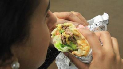 Una mujer disfruta de una creación culinaria de Taco Bell, conocida como 'burgrito', combinación de hamburguesa y burrito, en una imagen de archivo.