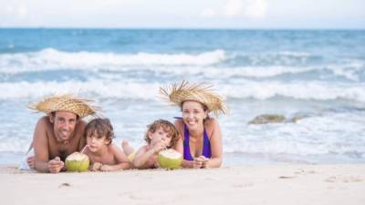 Happy family lying on the beach and drinking coconut drink