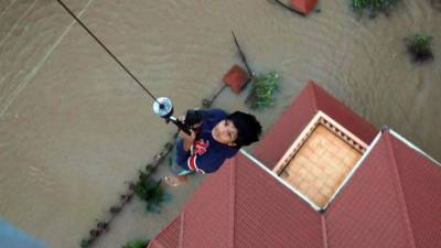 Un helicóptero rescata a un niño del techo de una casa.
