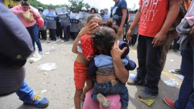 National Police riot police officers observe Honduran migrants moving to Agua Caliente, on the border between Honduras and Guatemala, on their way to the United States, on January 15, 2021. - Hundreds of asylum seekers are forming new migrant caravans in Honduras, planning to walk thousands of kilometers through Central America to the United States via Guatemala and Mexico, in search of a better life under the new administration of President-elect Joe Biden. (Photo by Orlando SIERRA / AFP)