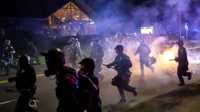 PORTLAND, OR - APRIL 12: Portland police officers chase demonstrators after a riot was declared during a protest against the killing of Daunte Wright on April 12, 2021 in Portland, Oregon. Wright, a Black man whose car was stopped in Brooklyn Center, Minnesota on Sunday reportedly for an expired registration, and not far from where George Floyd was killed during an arrest in Minneapolis last May, was shot and killed by an officer who police say mistook her service revolver for a Taser. Nathan Howard/Getty Images/AFP== FOR NEWSPAPERS, INTERNET, TELCOS & TELEVISION USE ONLY ==