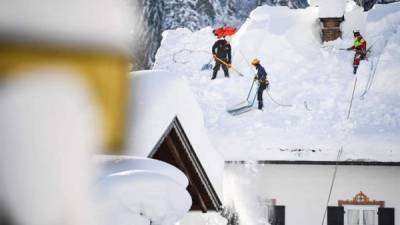 Operarios retiran la nieve de un tejado en Gerold, Alemania, hoy, 11 de enero de 2019. Las persistentes nevadas registradas en Múnich y en Fráncfort obligaron hoy a cancelar unos 200 vuelos, mientras se extienden las alertas por la previsión de nuevas precipitaciones en amplias zonas de Baviera. EFE