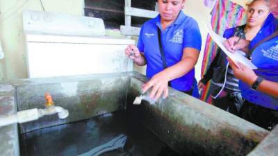 Personal de la Secretaría de Salud coloca abate en una pila de una vivienda localizada en Tegucigalpa.