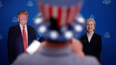 Un hombre fotografía carteles con los retratos de los candidatos a la Presidencia de Estados Unidos, Hillary Clinton y Donald Trump durante el evento 'Elecciones en EUA. EFE