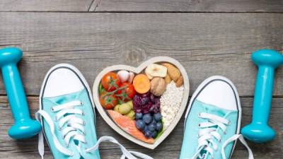 Healthy lifestyle concept with food in heart and sports fitness accessories on wooden boards