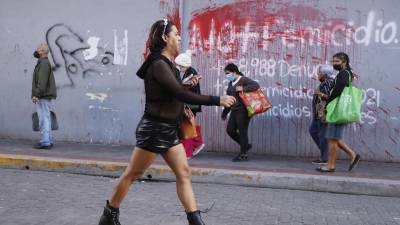 Elle de la comunidad LGBTI camina frente a un aviso pintado en una pared en contra del femicidio hoy en Tegucigalpa (Honduras). EFE