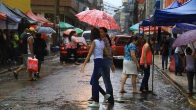 Ciudadanos se protegen de la lluvia en la 3 calle, 4 avenida, de El Centro.